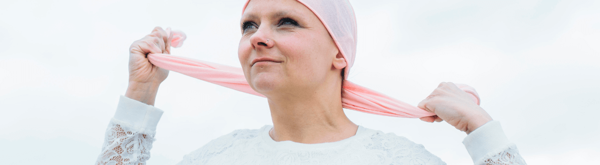 Cancer patient ties scarf on her head.